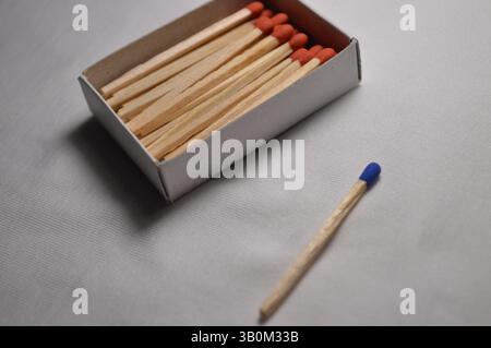 Une boîte d'allumettes se trouve sur une table avec une allumette posée à côté. Banque D'Images