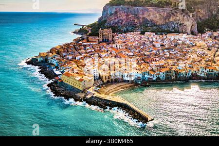 Une vue imprenable par drone capture la vieille ville de Cefalu au coucher du soleil, mettant en valeur son charme médiéval. La cathédrale de Cefalu se dresse majestueusement parmi les bâtiments rustiques le long de la côte. Banque D'Images