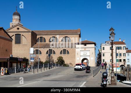 Chioggia, Italie - 3 mars 2025 : Porta Garibaldi et la cathédrale, avec des gens marchant dans le centre historique de la ville Banque D'Images