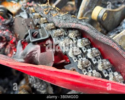 Gros plan d'une carte de circuit imprimé à LED fondue à l'intérieur d'un ensemble de feu arrière de voiture brûlé, montrant des composants électroniques endommagés et un boîtier en plastique rouge carbonisé Banque D'Images