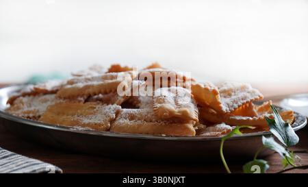 Saison du carnaval. Bonbons de carnaval italiens traditionnels faits maison. Chiacchiere saupoudré de sucre glace. Gros plan. Banque D'Images