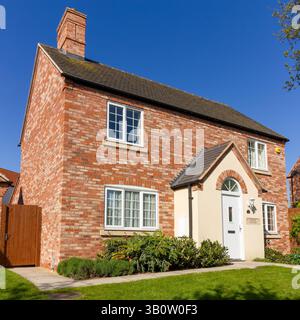 Nouvelle maison de construction dans le style traditionnel de chalet anglais construit à Ibstock Beamish mélange de briques rouges avec crème rendu porche et ciel bleu au-dessus, Angleterre, Royaume-Uni Banque D'Images