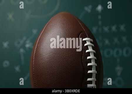Ballon de football américain contre le schéma de jeu flou, gros plan Banque D'Images