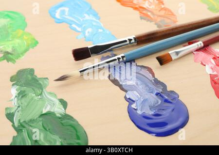 Palette en bois avec peintures et pinceaux, gros plan Banque D'Images