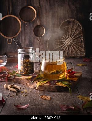 Pumpkin Spice Tea dans une tasse en verre clair, avec du thé frais stocké dans un pot en verre, dans une cuisine rustique Banque D'Images