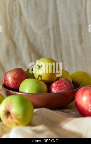 Nature morte de pommes vertes et rouges dans un bol brun Banque D'Images