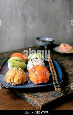 Temari sushi. Boules de sushi tendance avec saumon, avocat, concombre et omelette japonaise sur assiette bleue. Sauce soja, gingembre mariné, baguettes sur WO rustique Banque D'Images