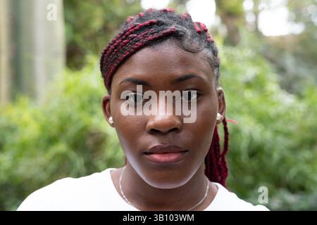 Un portrait montre une belle jeune femme aux cheveux tressés, placée sur un fond naturel paisible Banque D'Images