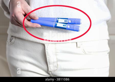 Femme en vêtements blancs tient un stylo d'injection Ozempic bleu avec un cercle rouge. Banque D'Images