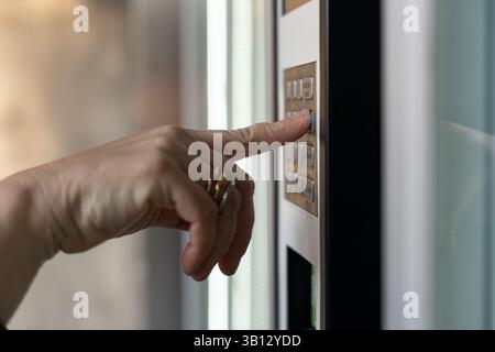 Gros plan de la main d'une femme appuyant sur un bouton sur un clavier, entrant un code de sécurité pour accéder à un bâtiment ou une zone d'accès restreint, améliorant la sécurité et le contr Banque D'Images