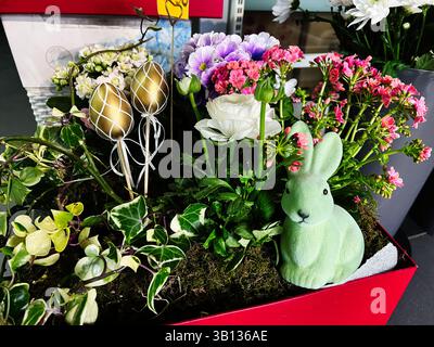 Décoration florale festive sur le thème de Pâques avec des fleurs vibrantes, des œufs décoratifs et des détails de lapin. Banque D'Images