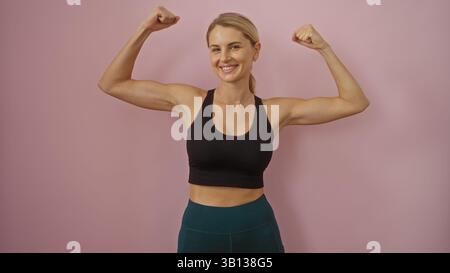 Femme fléchissant les muscles en toute confiance sur fond rose isolé, mettant en valeur la force et la forme physique dans un style moderne, attrayant et jeune, perfec Banque D'Images