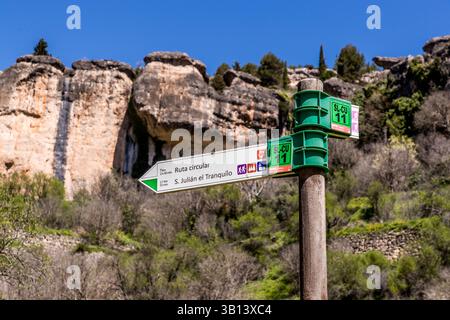 Un panneau indicateur pour l'itinéraire circulaire vers S. Julián el Tranquilo se dresse devant des formations de calcaire accidentées sur le Camino de San Isidro près de Cuenca, Castilla-La Mancha, Espagne. Des tours rocheuses érodées aux formes caractéristiques forment l'arrière-plan. Banque D'Images