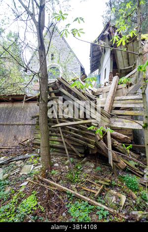 Bad Illstern, italie., lieu perdu. Structure en bois délabrée avec un bâtiment en bois et en pierre effondré en arrière-plan au milieu d'une végétation envahie Banque D'Images