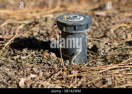 tête d'arrosage noire délavée dans le sol Banque D'Images