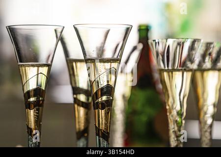 Gros plan de verres à champagne remplis ou de gobelets à champagne contre la lumière, couleurs floues en arrière-plan Banque D'Images