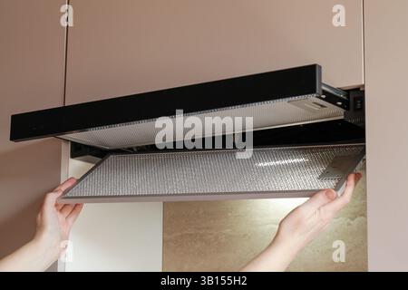 Remplacement du filtre à charbon qui élimine les odeurs dans la cuisine dans la hotte. Ventilation constante Banque D'Images