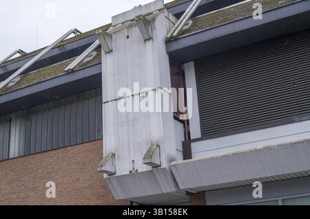 Détail architectural de l'extérieur d'un bâtiment mettant en évidence le béton, les intempéries, la croissance de la mousse et les tuyaux métalliques contre une façade en briques, Borken, NRW, Germa Banque D'Images