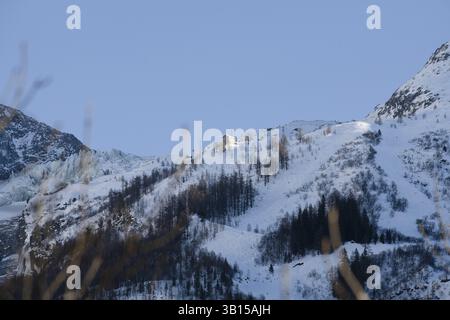 Chalet niché dans les montagnes enneigées sous un ciel bleu clair, entouré d'arbres et de remontées mécaniques, montagne enneigée, Chamonix, France, Europe Banque D'Images