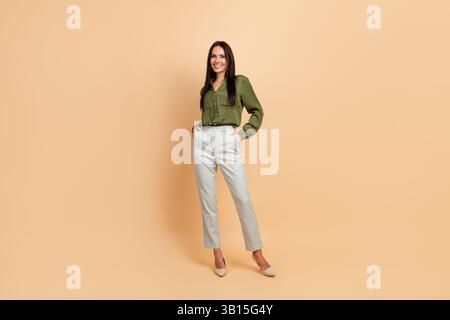 Jeune femme professionnelle en tenue formelle souriant avec confiance sur fond beige, représentation élégante et élégante pour les affaires Banque D'Images