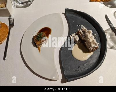 Une expérience gastronomique est présentée avec deux plats élégamment agencés sur une nappe blanche, mettant en valeur l'art culinaire. Banque D'Images