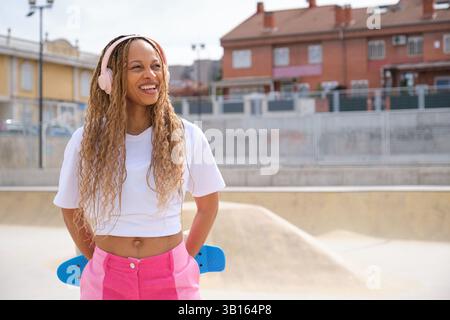 Patineur élégant souriant et écoutant de la musique dans un skate Park Banque D'Images
