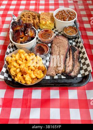 Plateau barbecue avec poitrine, côtés et sauces sur un plateau à carreaux. Banque D'Images