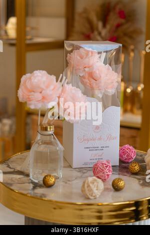 Élégant diffuseur de roseaux floraux avec des roses artificielles roses douces et des accents décoratifs sur une table en marbre et or, créant une maison luxueuse et confortable. Banque D'Images
