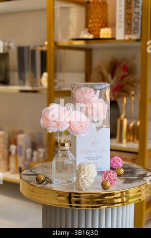 Élégant diffuseur de roseaux floraux avec des roses artificielles roses douces et des accents décoratifs sur une table en marbre et or, créant une maison luxueuse et confortable. Banque D'Images