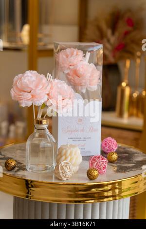 Élégant diffuseur de roseaux floraux avec des roses artificielles roses douces et des accents décoratifs sur une table en marbre et or, créant une maison luxueuse et confortable. Banque D'Images