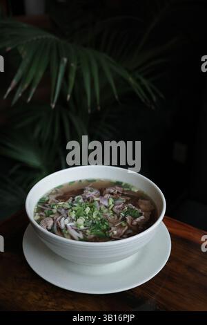 Soupe pho vietnamienne traditionnelle avec tranches de bœuf servies dans un bol en céramique blanche. Concept de cuisine asiatique authentique, nourriture saine et réconfortante Banque D'Images