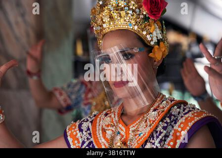 Les danseurs de cérémonie du sanctuaire Erawan de Bangkok portent des visières en plastique pour se protéger contre Covid 19 Banque D'Images