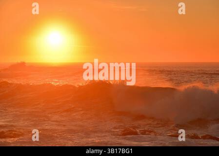 Coucher de soleil sur l'océan Atlantique avec des tons jaunes dorés et des vagues jetées par le vent Banque D'Images