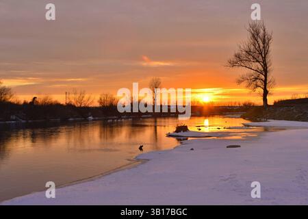 Coucher de soleil sur la rivière Mures un jour d'hiver avec des silhouettes d'arbres et de neige sur les berges Banque D'Images