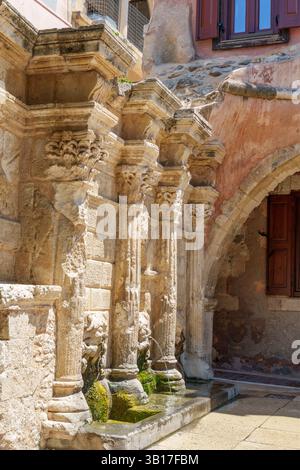 La fontaine Rimondi, monument de l'époque vénitienne avec des sculptures ornées et des becs à tête de lion, orne un coin ensoleillé de la vieille ville de Réthymnon, en Crète, en Grèce. Banque D'Images