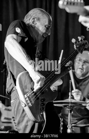 Norman Watt-Roy joue de la basse avec passion sur scène avec Ted Duggan à la batterie, illuminé par un éclairage de scène dans une image en noir et blanc à Half Moon. Banque D'Images