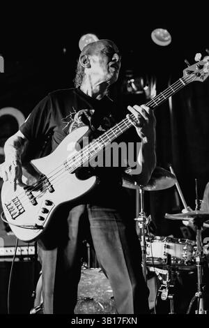 Norman Watt-Roy joue de la basse avec passion sur scène, illuminé par un éclairage dramatique dans un sombre et atmosphérique Half Moon, Putney. Banque D'Images