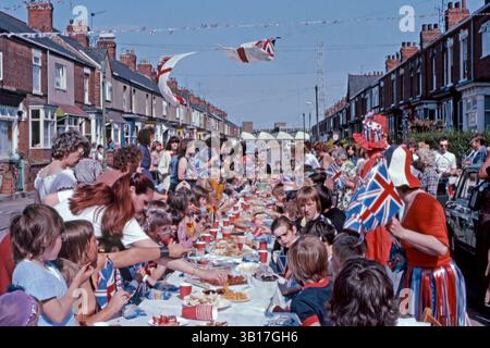 Tout au long du Royaume-Uni, des fêtes de rue célébrant le mariage du prince Charles (futur roi Charles III) et de Lady Diana Spencer, qui a eu lieu à la cathédrale Saint-Paul de Londres le mercredi 29 juillet 1981. Il y avait une fête nationale ce jour-là pour marquer le mariage. Ici, un déjeuner en plein air pour enfants a été préparé, avec des boissons gazeuses, de la nourriture pour les doigts et des sacs de chips Walkers. Des drapeaux de l'Union Jack en plastique sont distribués et des drapeaux blancs et des banderoles flottent dans la brise. Banque D'Images