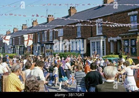 Tout au long du Royaume-Uni, des fêtes de rue célébrant le mariage du prince Charles (futur roi Charles III) et de Lady Diana Spencer, qui a eu lieu à la cathédrale Saint-Paul de Londres le mercredi 29 juillet 1981. Il y avait une fête nationale ce jour-là pour marquer le mariage. Ici, les enfants et les adultes dansent dans la rue. Les drapeaux et chapeaux de l'Union jack sont exposés et les drapeaux et banderoles blancs flottent dans la brise. Banque D'Images