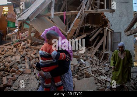 Une femme cachemirie portant son fils marche près de la maison démolie apparentée à la famille d'Adil Hussain Thokar, soupçonnée d'avoir participé à l'attaque touristique de Pahalgam, à Bijbehera Anantnag, au sud de Srinagar. Des soldats dans le Cachemire administré par l'Inde ont fait exploser les maisons familiales de deux hommes à Tral et Bijbhera, qui, selon la police, faisaient partie du gang qui a mené l'attaque la plus meurtrière de la région contre des civils depuis des décennies. Les forces indiennes ont lancé une chasse à l'homme massive pour les responsables de la mort de 26 touristes, dont deux ressortissants étrangers, dans un pré hors route dans la pittoresque ville de Pahalgam. Banque D'Images