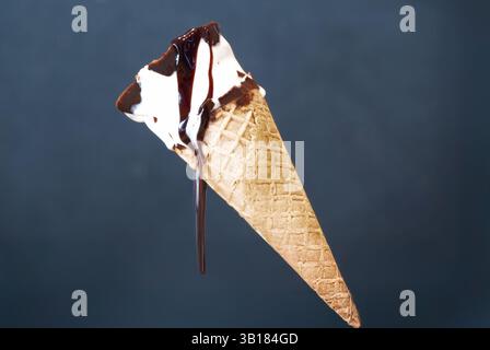 Un cornet de crème glacée à la vanille, arrosé de sirop de chocolat, fond dans la chaleur. La gourmandise sucrée est une gourmandise estivale classique, Banque D'Images