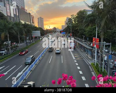 Nanning, Chine - 8 octobre 2023. Coucher de soleil sur une rue animée de la ville à Nanning, Chine avec des voitures, des bus et des bâtiments crée une scène dynamique. Banque D'Images