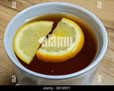 Deux tranches de citron flottant dans une tasse de thé noir, ajoutant une touche d'agrumes à une boisson réconfortante Banque D'Images