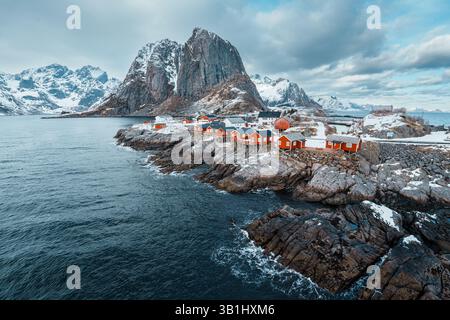 Vue panoramique de Hamnoy sur l'île des Lofoten avec des montagnes enneigées en arrière-plan au coucher du soleil. Banque D'Images