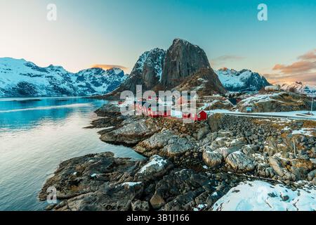 Vue panoramique de Hamnoy sur l'île des Lofoten avec des montagnes enneigées en arrière-plan au coucher du soleil. Banque D'Images