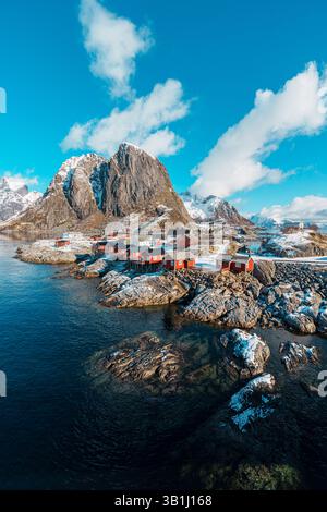 Vue panoramique de Hamnoy sur l'île des Lofoten avec des montagnes enneigées en arrière-plan au coucher du soleil. Banque D'Images