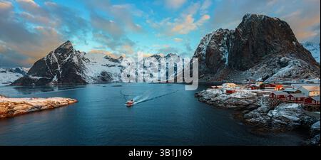 Vue panoramique de Hamnoy sur l'île des Lofoten avec des montagnes enneigées en arrière-plan au coucher du soleil. Banque D'Images