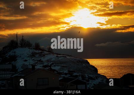 Vue panoramique sur Hamnoy avec des montagnes enneigées en arrière-plan au coucher du soleil. Banque D'Images