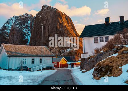 Vue panoramique de Hamnoy sur l'île des Lofoten avec des montagnes enneigées en arrière-plan au coucher du soleil. Banque D'Images
