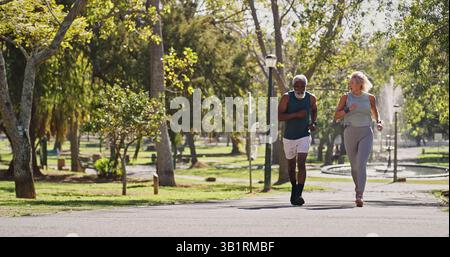 Fitness, couple de personnes âgées et courir dans le parc pour le bien-être, l'exercice cardio et l'entraînement à la retraite. Personnes âgées, sourire et plein air pour l'entraînement Banque D'Images